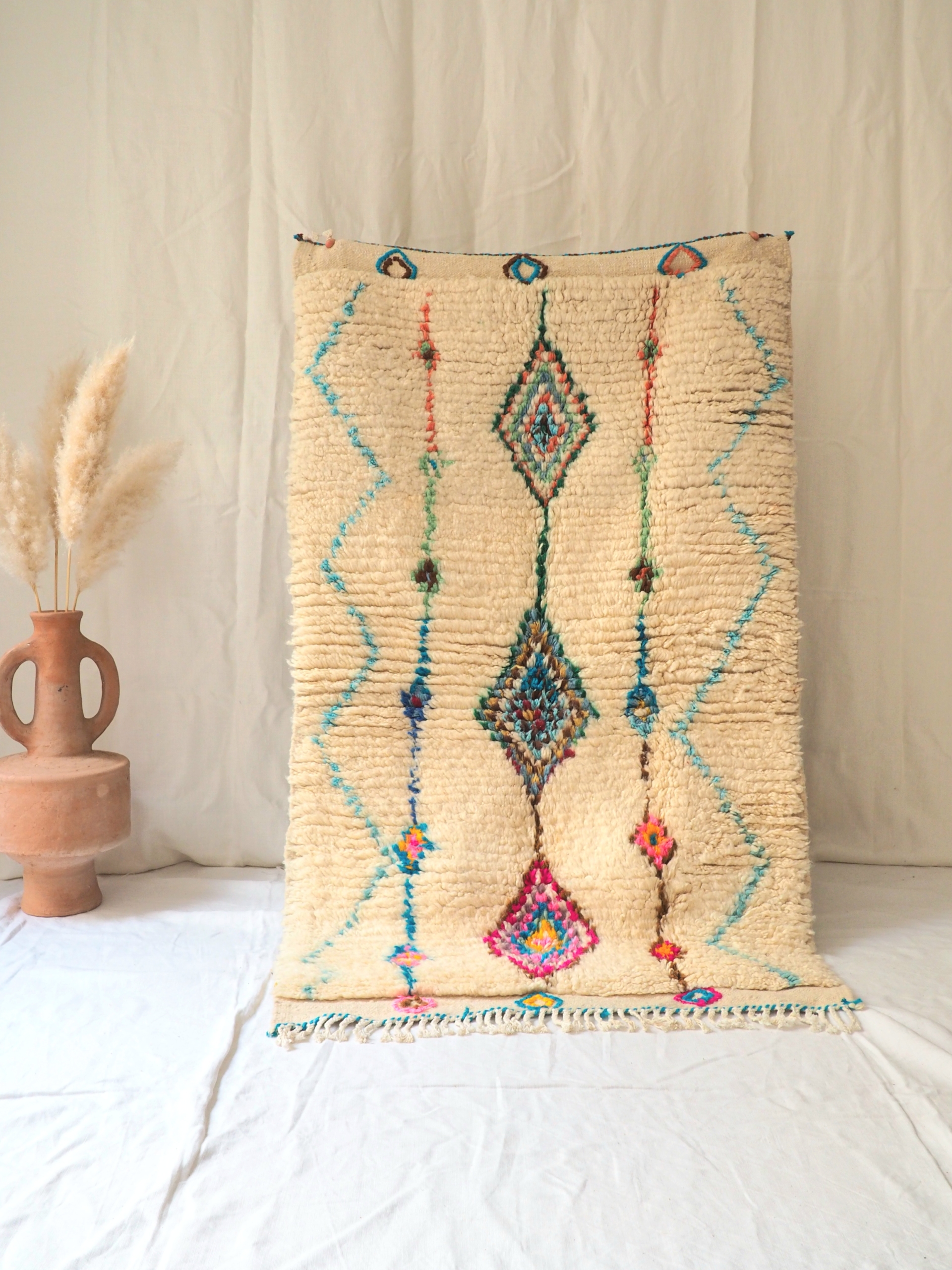 Vrai tapis Berbère en laine fond blanc cassé et motifs de couleurs vives fait main au Maroc